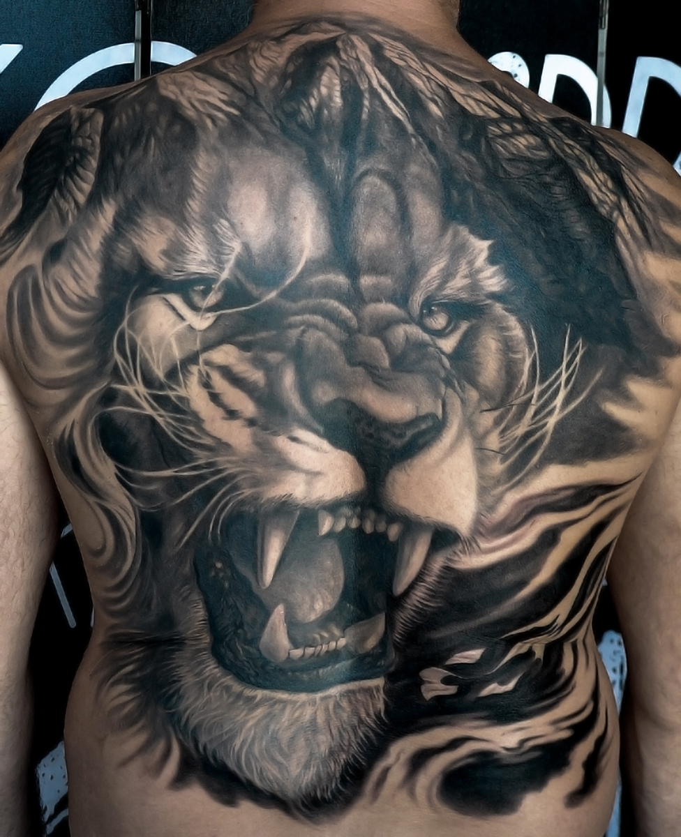 Espalda completa con un león en realismo black & grey, obra de Christian Esposito